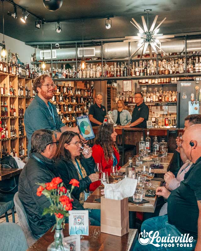 Tour guide and group at Taste Fine Wine and Bourbons on the Bourbon Food Tour in NuLu with Louisville Food Tours Louisville Kentucky
